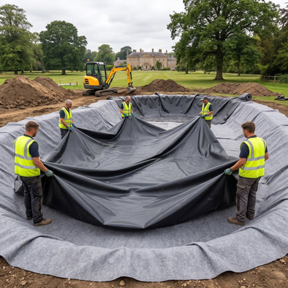 Landscaping crew spreading a large black butyl pond liner over grey geotextile underlay in a big estate pond excavation