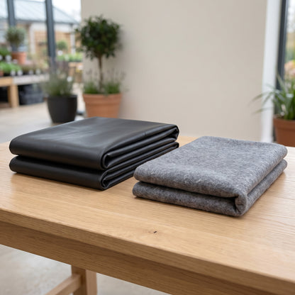 Folded black butyl pond liner and folded grey geotextile underlay side by side on a wooden table