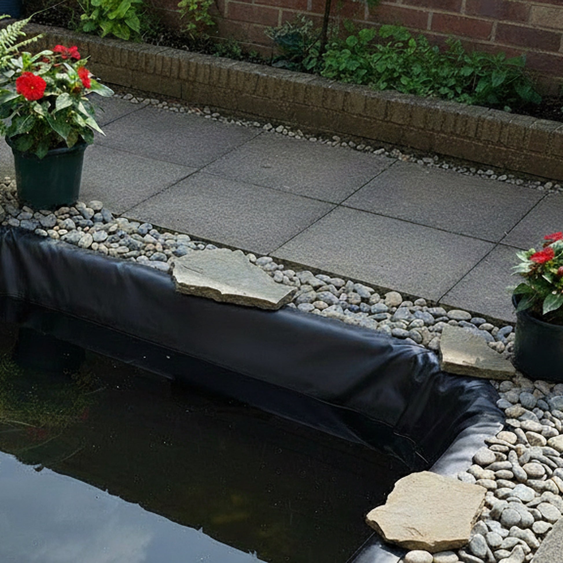 Small pond liner installed in patio garden pond with pebbles
