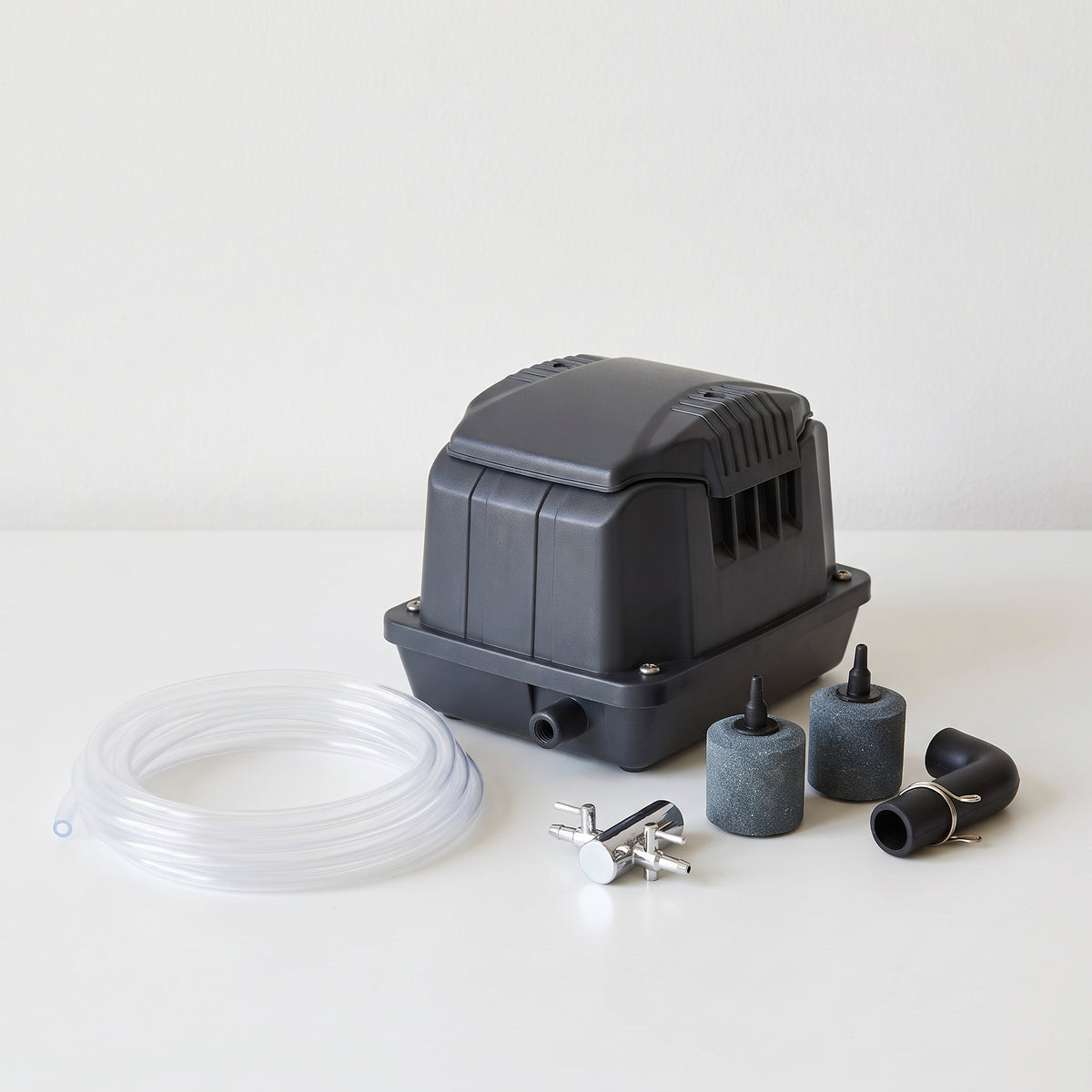 Pond air pump kit with clear airline, two cylindrical air stones, two-way air valve and elbow connector on a plain neutral background