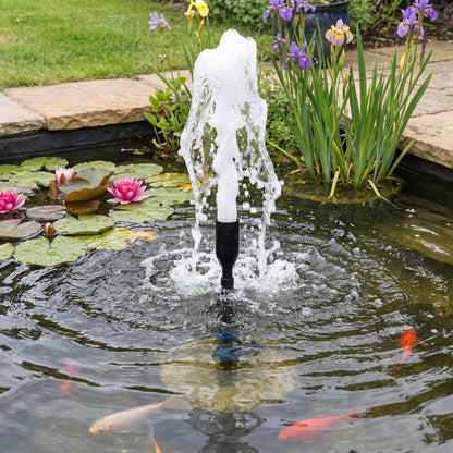 Pond fountain nozzle kit in a garden pond, the bottle-shaped foaming jet head throwing up a white aerated water column among water lilies and irises