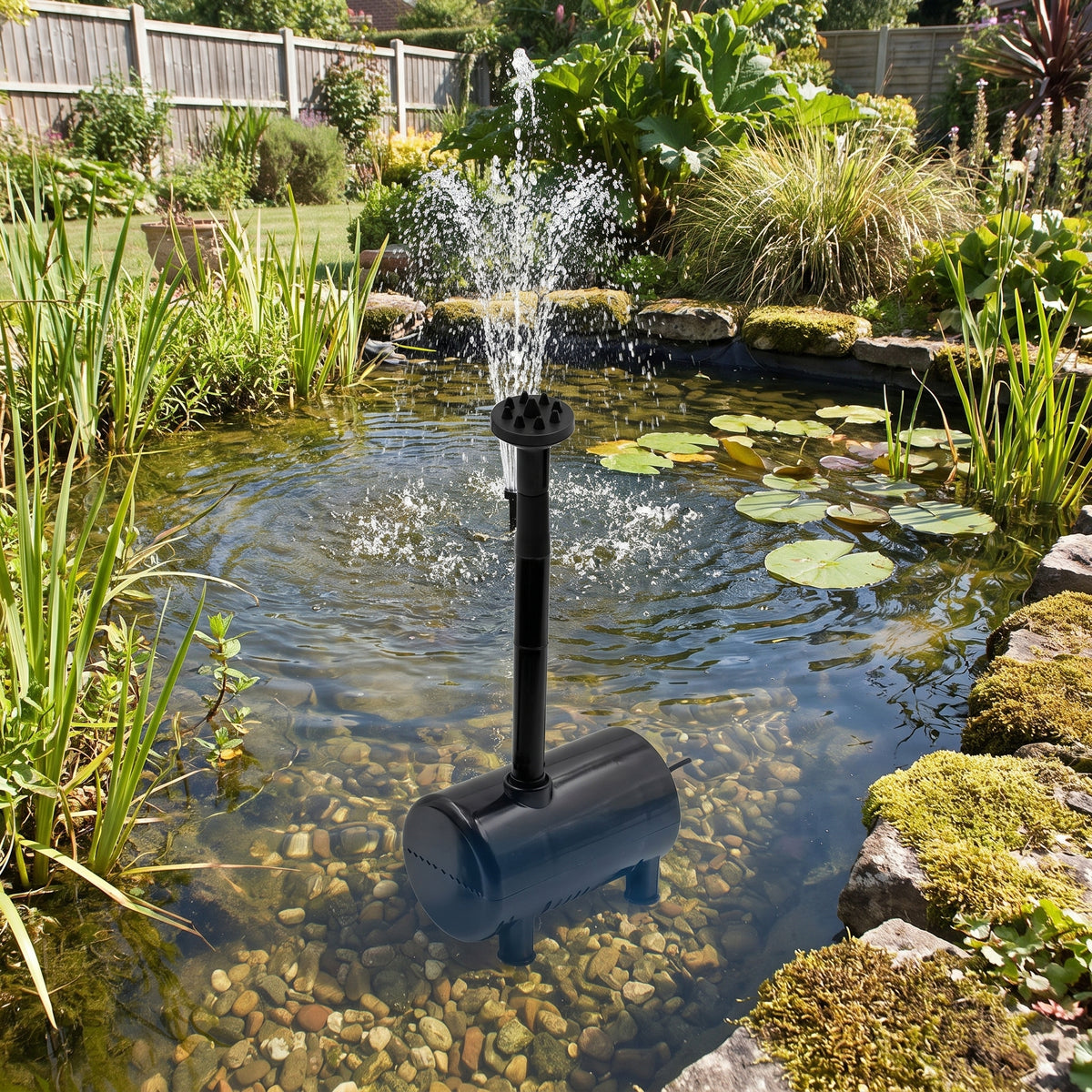 Solar fountain pump submerged in a clear garden wildlife pond, riser and spray head throwing a fountain among water lilies